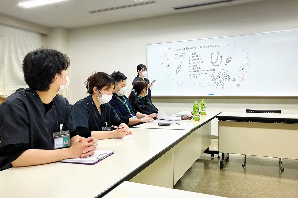 ステーションの一室で、看護師たちがホワイトボードを囲んで話し合っている様子