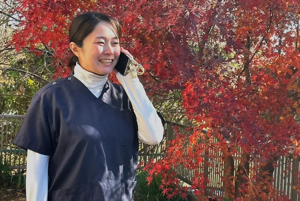 屋外でスマートフォンを耳にあて笑顔で話す看護師