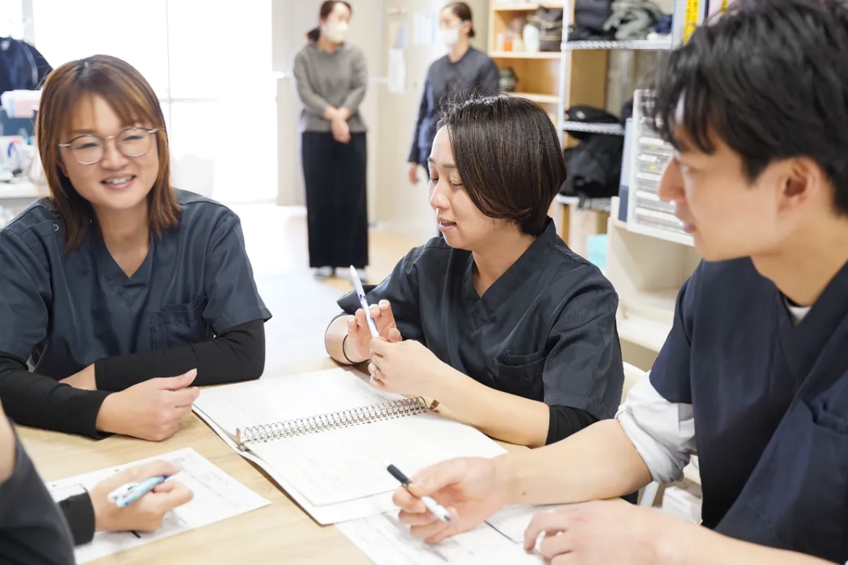 ノートを広げて、3人の看護師が話しながら学び合っている様子