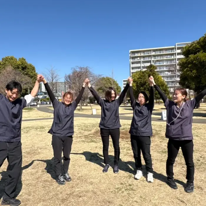 公園で手をつないで両手を上げるスタッフたち