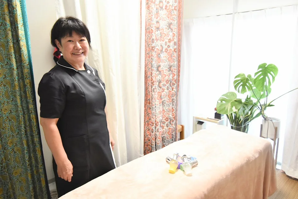 サロン「月の女神」の施術室で、施術着姿の貫田昌香