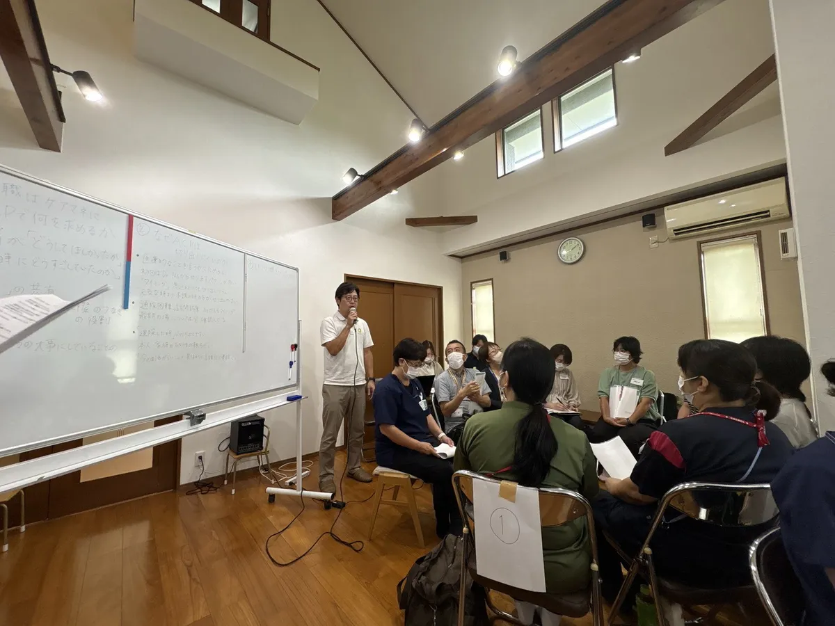 2026年9月15日 第4回交流会。ホワイトボードの前で話す講師と、グループで聞く参加者