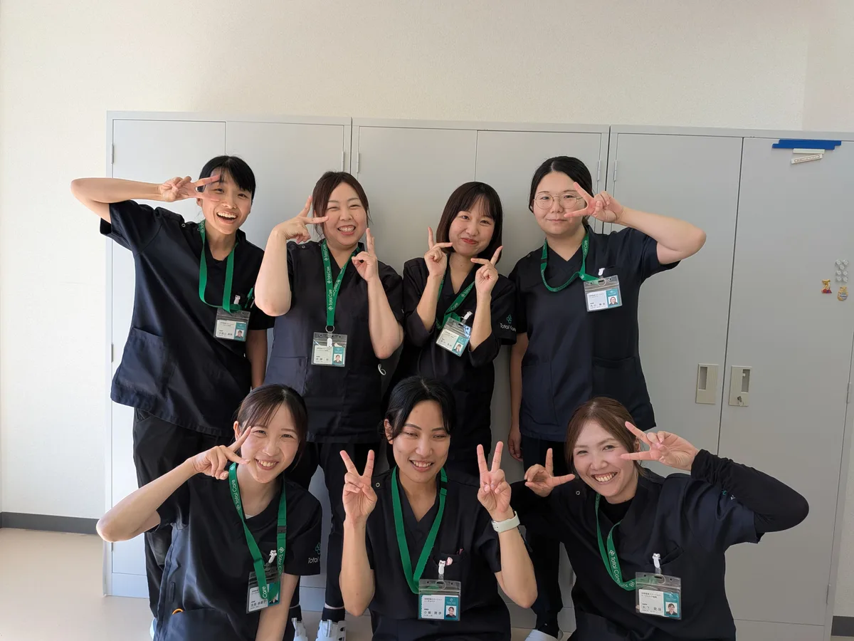 ステーションの中で、7人の看護師が並んでピースサインをする