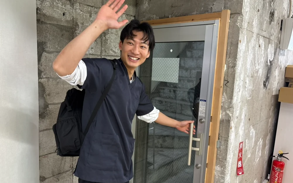 訪問へ出かける看護師。玄関で手を振って見送られる