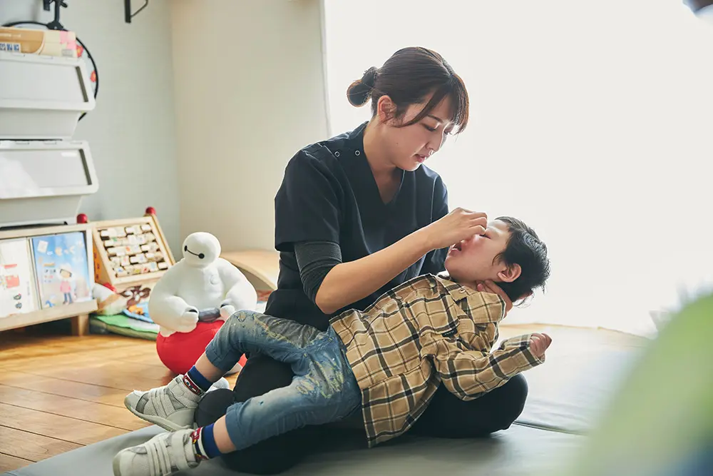 自宅のリビングで、看護師が子どもの様子を見ている