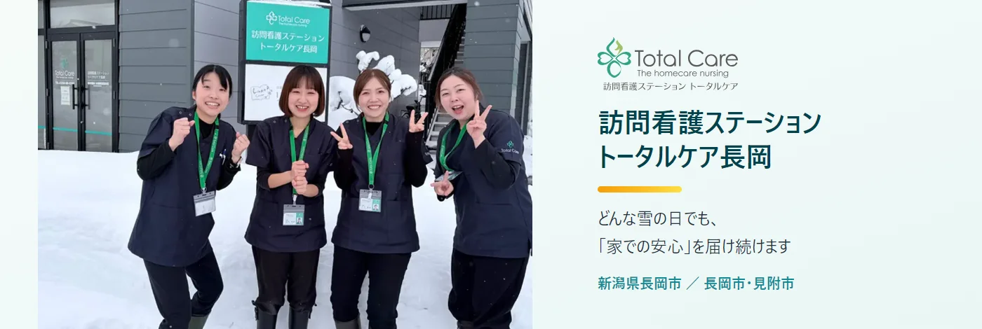 訪問看護ステーション トータルケア長岡。どんな雪の日でも「家での安心」を届け続けます。新潟県長岡市、訪問エリアは長岡市・見附市。雪の日に看板前に並ぶスタッフ4人