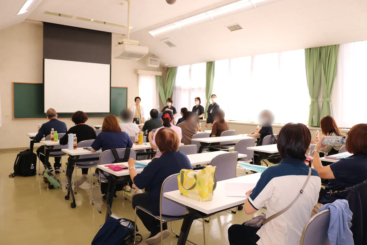 2026年10月16日 鶴ヶ島の交流会。前に立つ講師とトータルケア鶴ヶ島の看護師、席で話を聞くケアマネジャーのみなさん