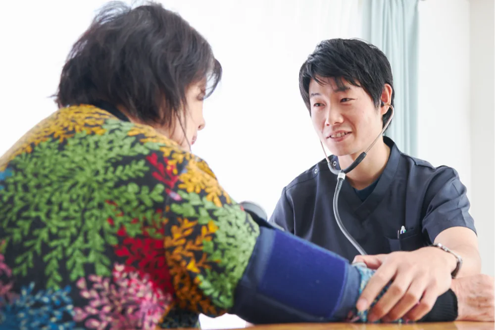 ご自宅で血圧を測りながら体調を確認する看護師
